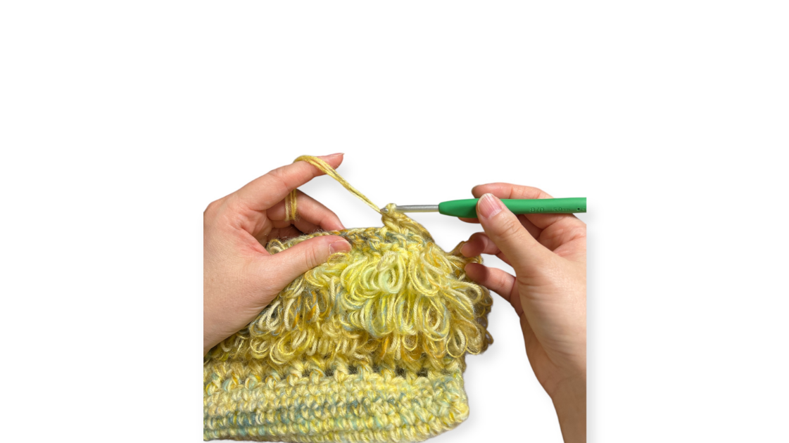 糸を持つ手が編み地（編んだ布地の部分）を固定している画像