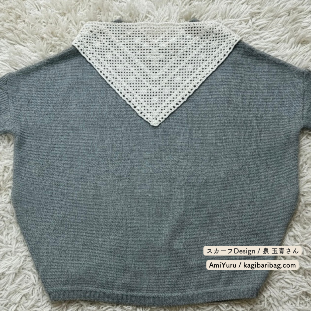 ウール糸を使って、かぎ針で編む方眼編みの三角スカーフをグレーの服と合わせた画像。